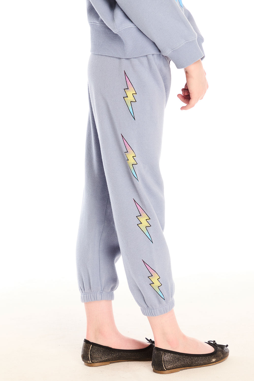 Side view of girl wearing Chaser’s blue-gray Pastel Love Bolt Pants with colorful accents on a white background