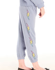 Side view of girl wearing Chaser’s blue-gray Pastel Love Bolt Pants with colorful accents on a white background