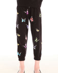 Young girl wearing Chaser’s Butterfly Love pants with colorful butterfly patterns on a white background