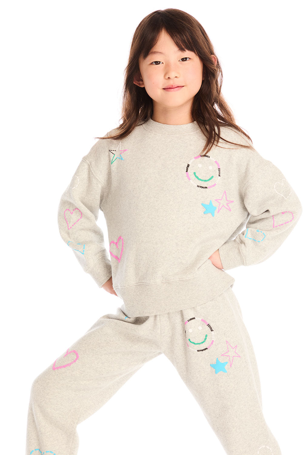 Girl wearing Chaser’s light gray Winter Love Stitches Long Sleeve with colorful designs on a white background