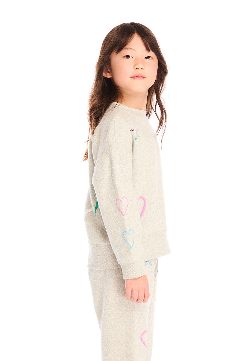 Side view of girl wearing Chaser’s light gray Winter Love Stitches Long Sleeve with colorful designs on a white background