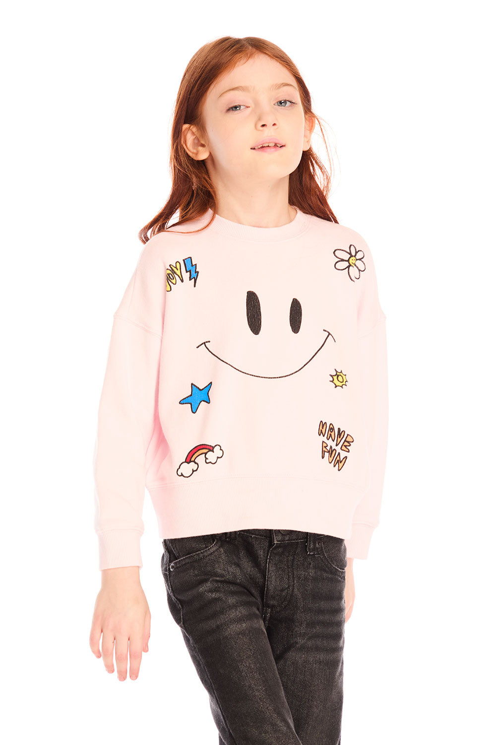 Young girl wearing Chaser’s pink Be Happy Icons long sleeve pullover with smiley face design on a white background
