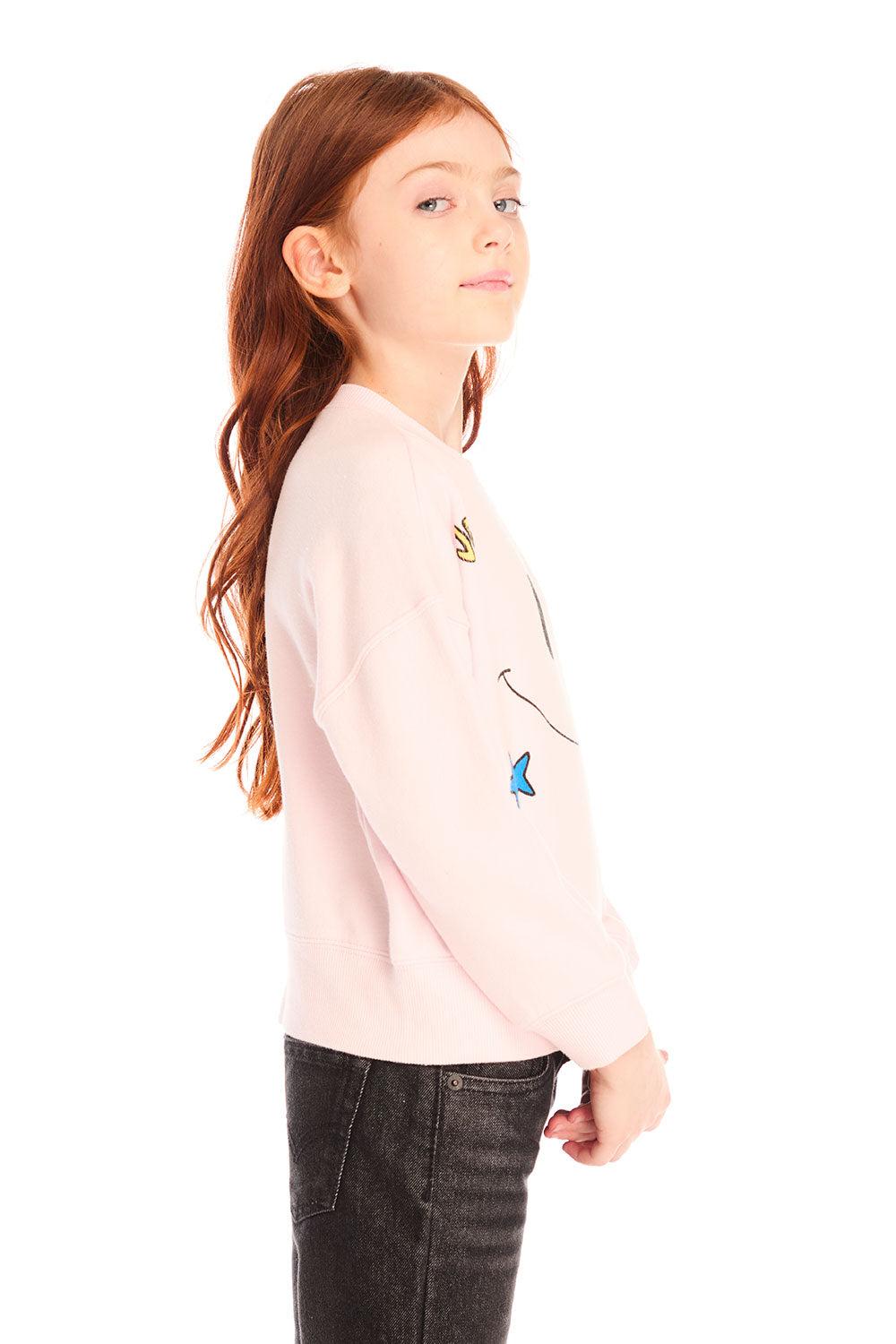 Side view of young girl wearing Chaser’s pink Be Happy Icons long sleeve pullover with smiley face design on a white background