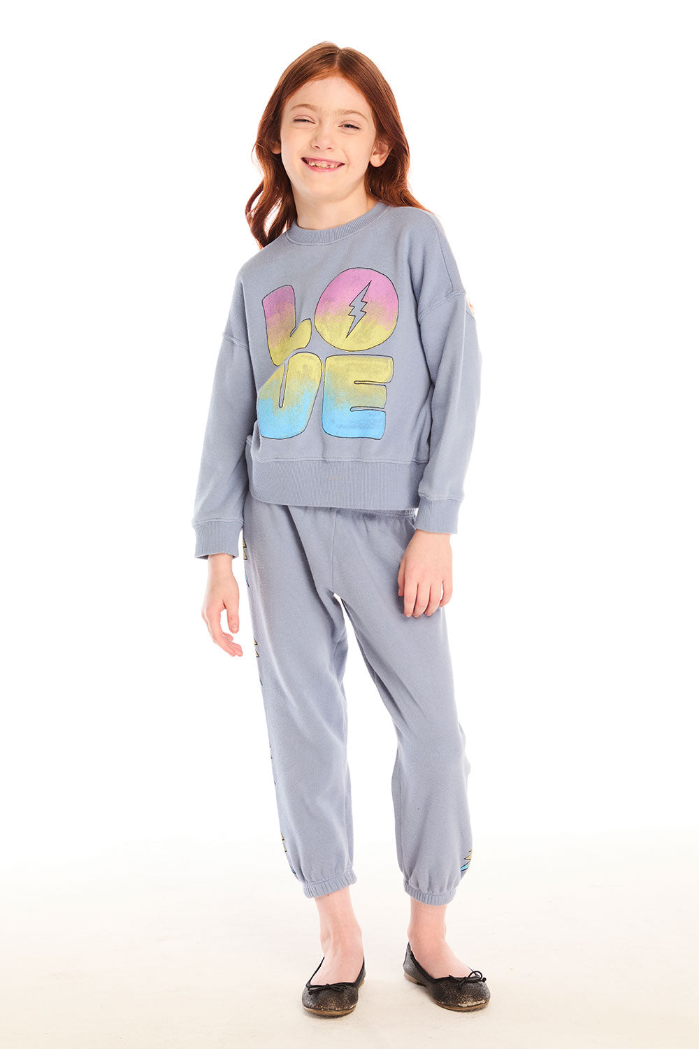 Full body view of girl wearing Chaser’s blue-gray Pastel Love Bolt Long Sleeve with colorful “LOVE” design and matching pants on a white background