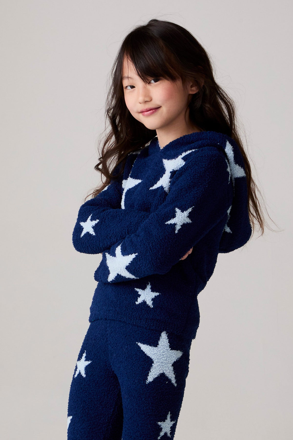 Model wearing Chaser's Allover Stars Girls Hoodie in lake blue with star detailing, side view
