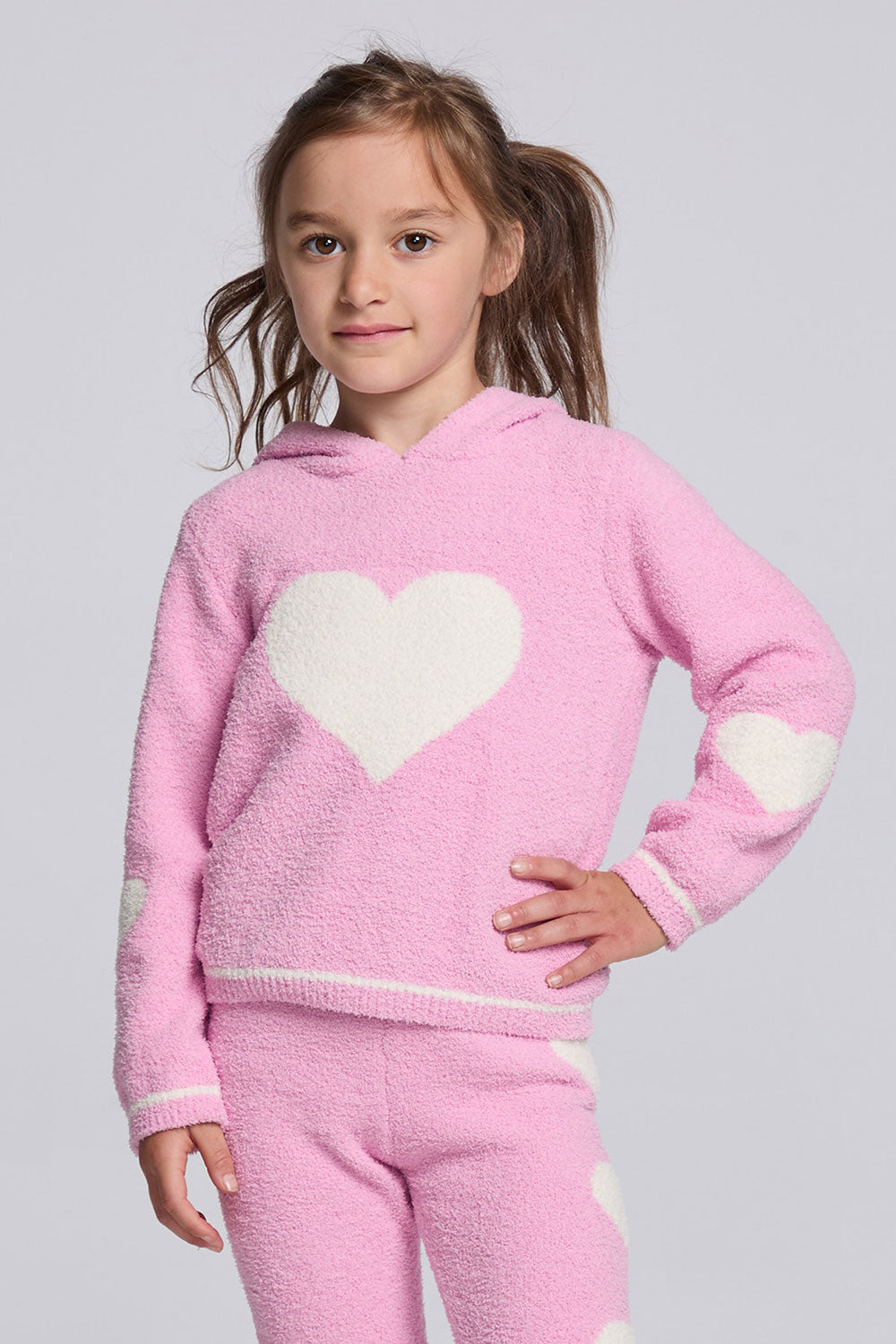 Chaser Kids Holiday Hug Girls Hoodie in pink with white hearts, front view on a model against a light gray studio background