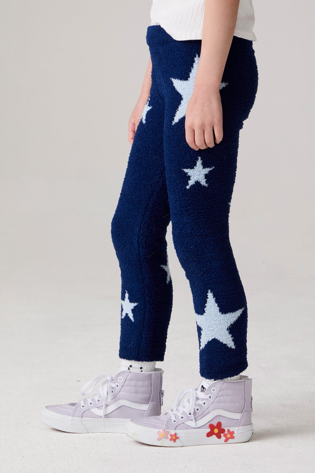 Model wearing Chaser's Allover Stars Girls Pants in lake blue with star detailing, side view