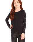 Girl wearing Chaser’s black Love Stitch Hearts Long Sleeve with heart patterns on sleeves and dark jeans on a white background