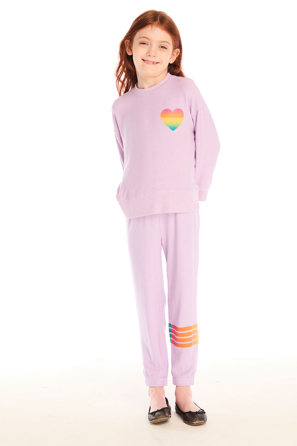 Full body view of girl wearing Chaser’s pink Rainbow Glitter Heart Pullover with rainbow heart design and matching pants on a white background