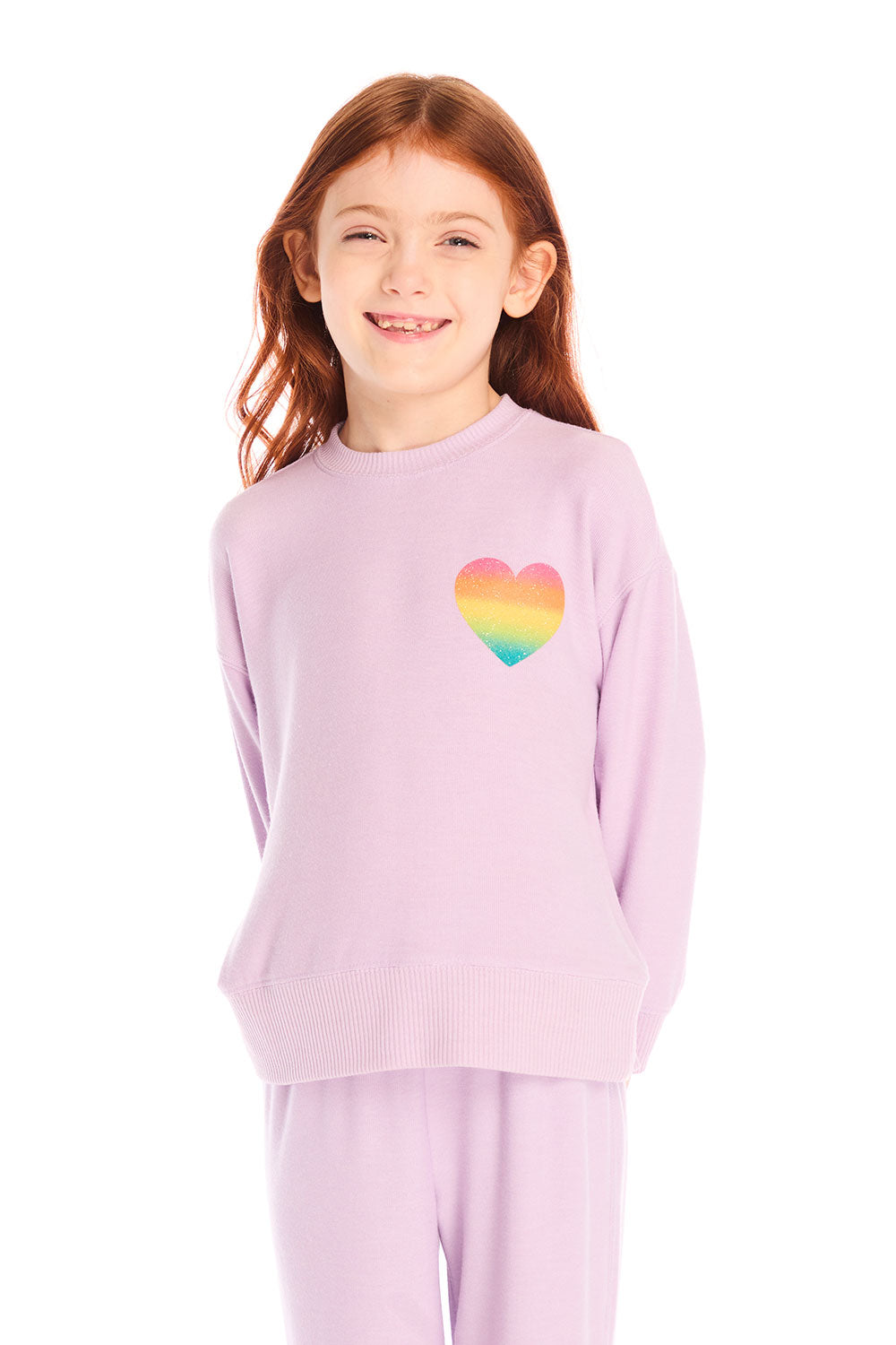 Girl wearing Chaser’s pink Rainbow Glitter Heart Pullover with rainbow heart design on a white background