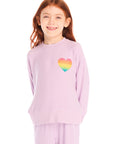 Girl wearing Chaser’s pink Rainbow Glitter Heart Pullover with rainbow heart design on a white background