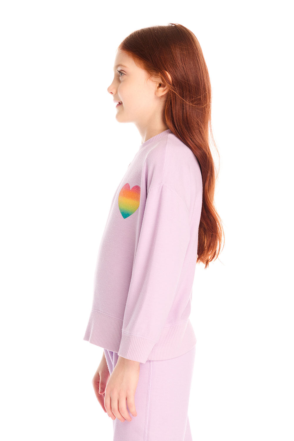 Side view of girl wearing Chaser’s pink Rainbow Glitter Heart Pullover with rainbow heart design on a white background