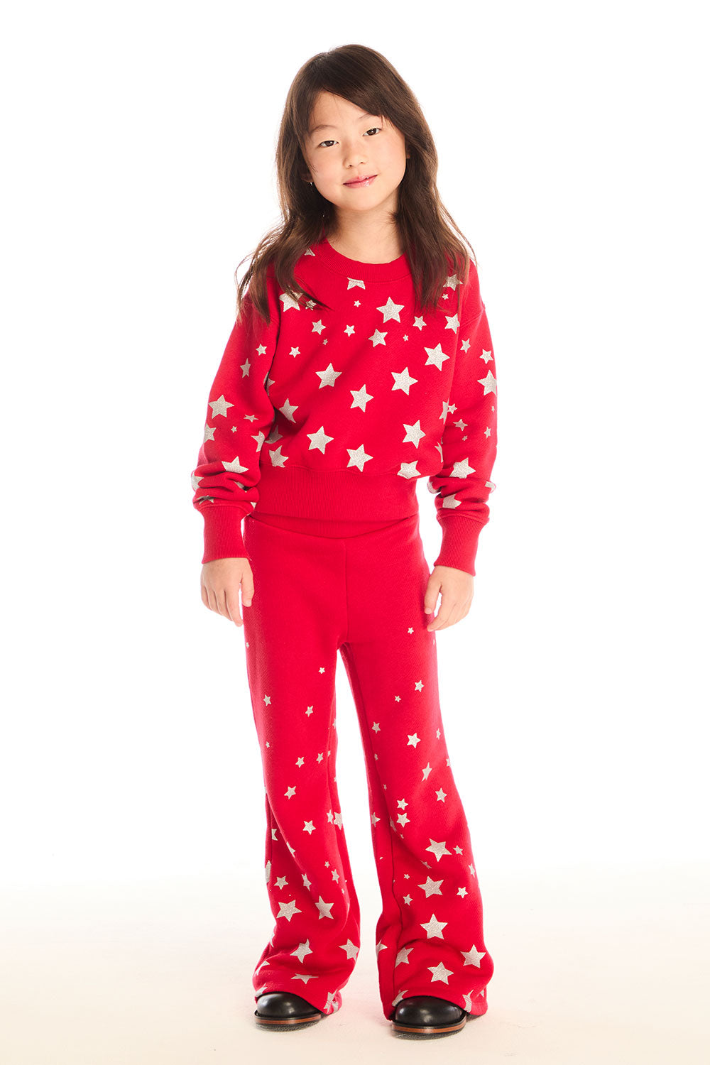 Full body view of girl wearing Chaser’s Danni Rouge Pullover with star patterns and matching Tara Leggings on a white background