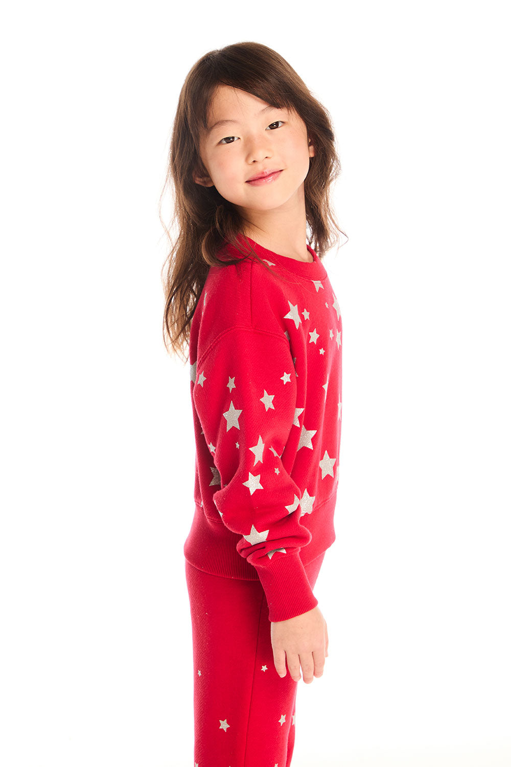 Side view of girl wearing Chaser’s Danni Rouge Pullover with star patterns and matching Tara Leggings on a white background