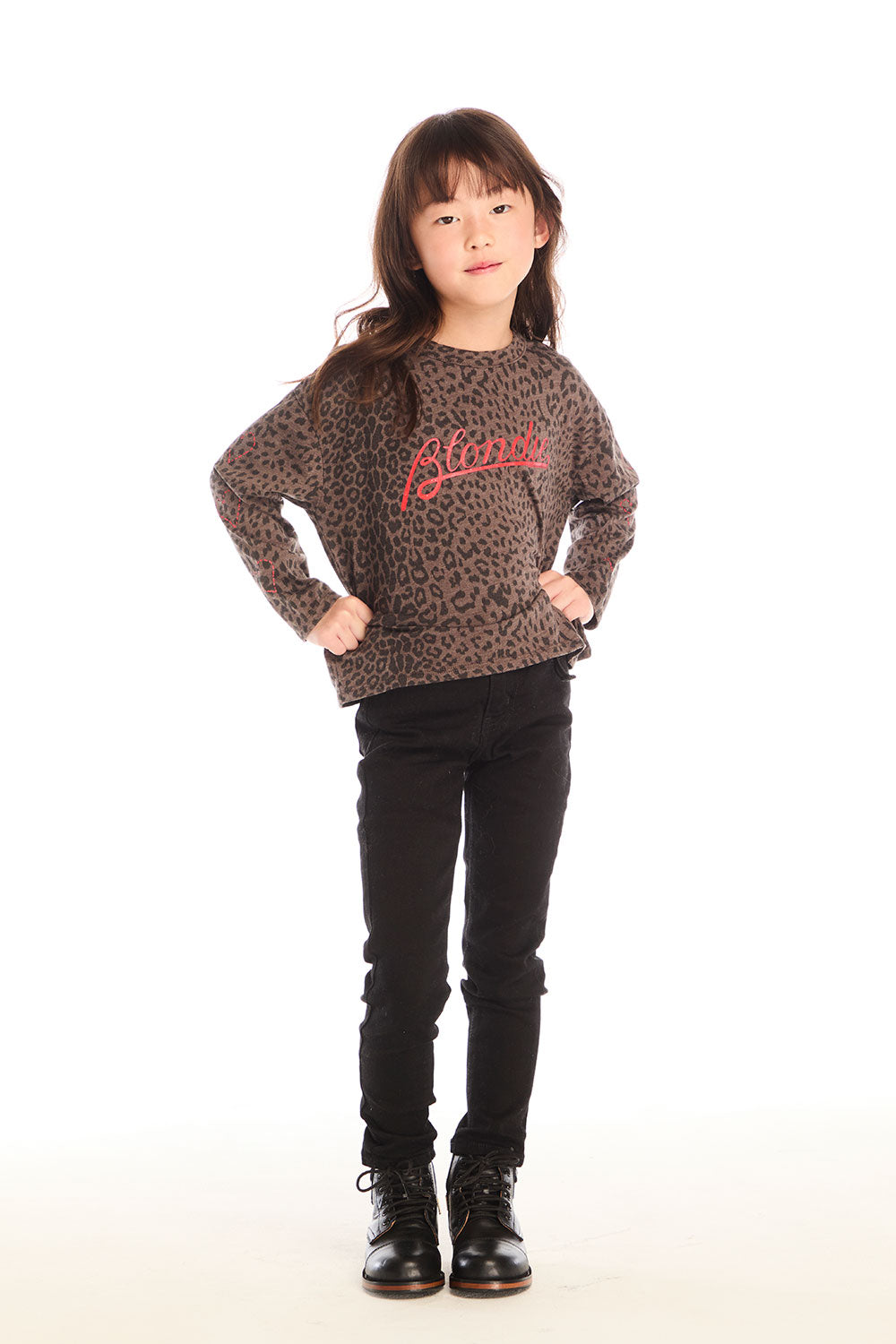 Full body view of girl wearing Chaser’s Blondie Leopard & Hearts print pullover top with red text and black pants on a white background