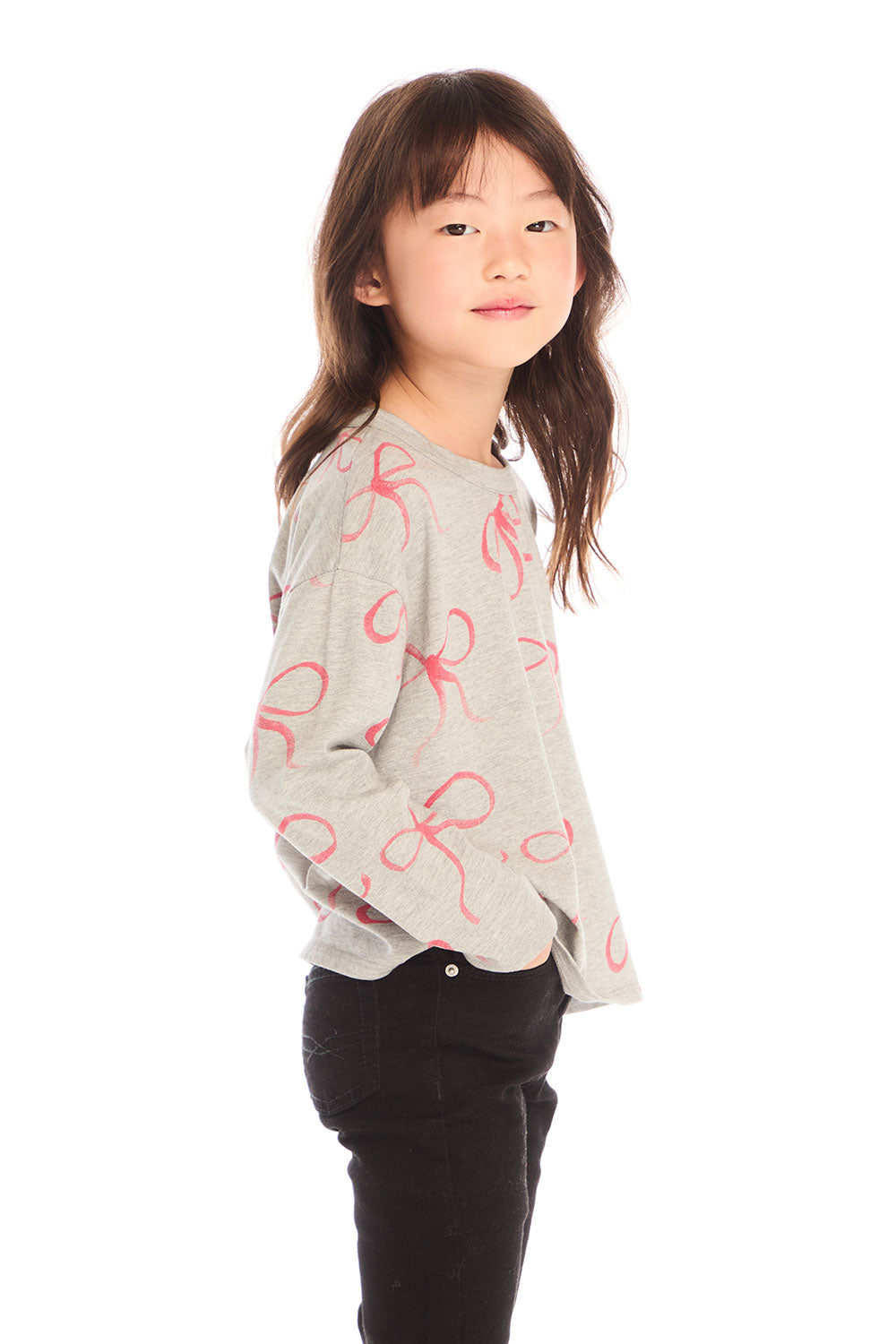 Side view of girl wearing Chaser’s gray Red Bows Long Sleeve with pink bow pattern on a white background
