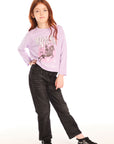 Full body view of girl wearing Chaser’s pink Willie Nelson Lady Luck Tee with text and graphics, black pants, and black sneakers on a white background