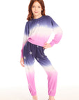 Full body view of girl wearing Chaser’s Slim Ombre Tie Dye Pants with colorful glitter star patterns and matching long sleeve top on a white background