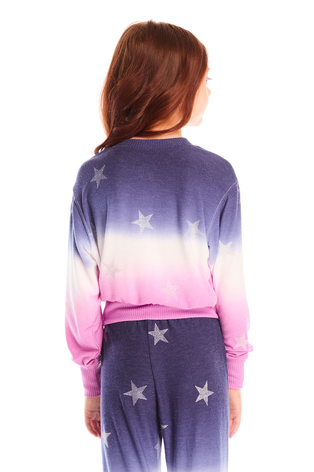 Back view of girl wearing Chaser’s Glitter Stars Ombre Tie Dye Long Sleeve with colorful star patterns and matching pants on a white background