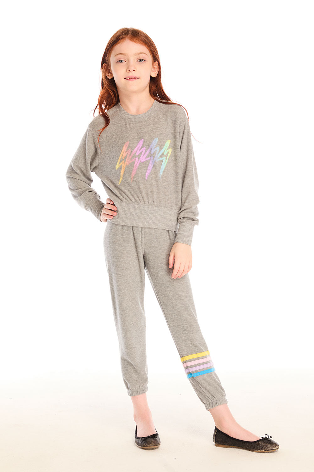 Full body view of girl wearing Chaser’s Heather Grey Contrast Strappings Pants with colorful accents on the left leg and Rainbow Bolts pullover on a white background
