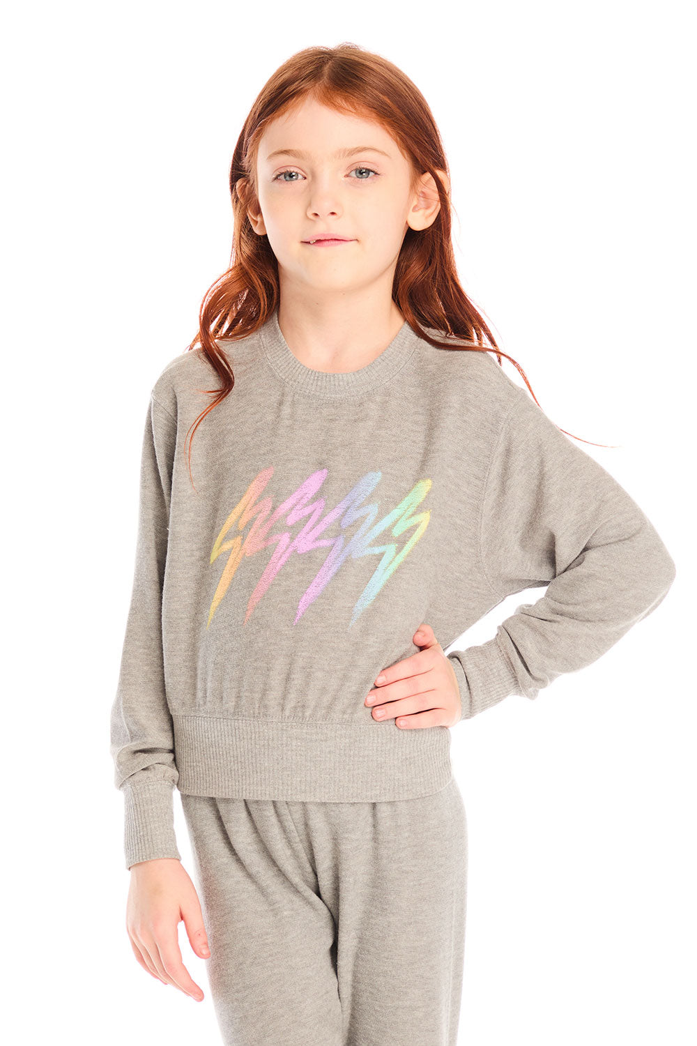 Girl wearing Chaser’s Rainbow Bolts Pullover in heather grey with colorful lightning bolt designs on a white background