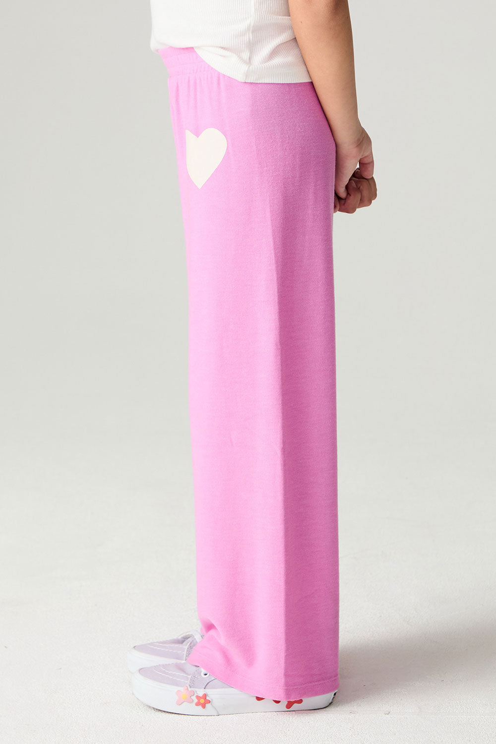 Side view of a girl wearing the Chaser Love Is Everywhere Girls Pants Jogger with white tee shirt and arms clasped 