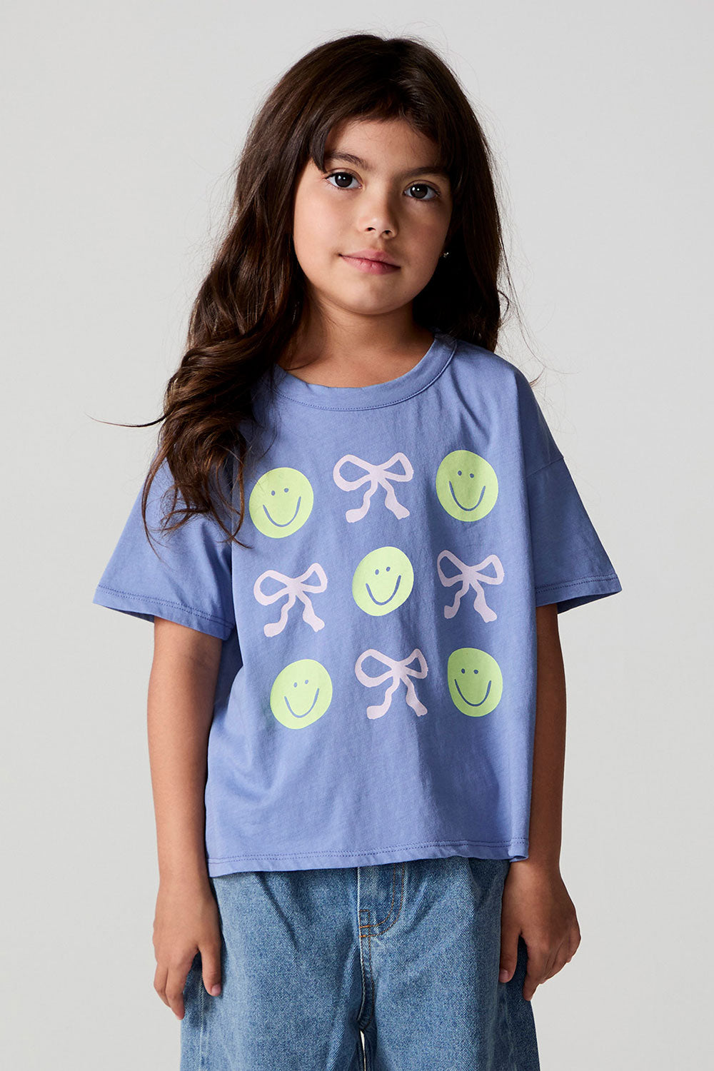 Front view of a girl wearing the Chaser Happy Bows Tee on a neutral background

