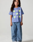 Full body front view of a girl wearing the Chaser Happy Bows Tee on a neutral background