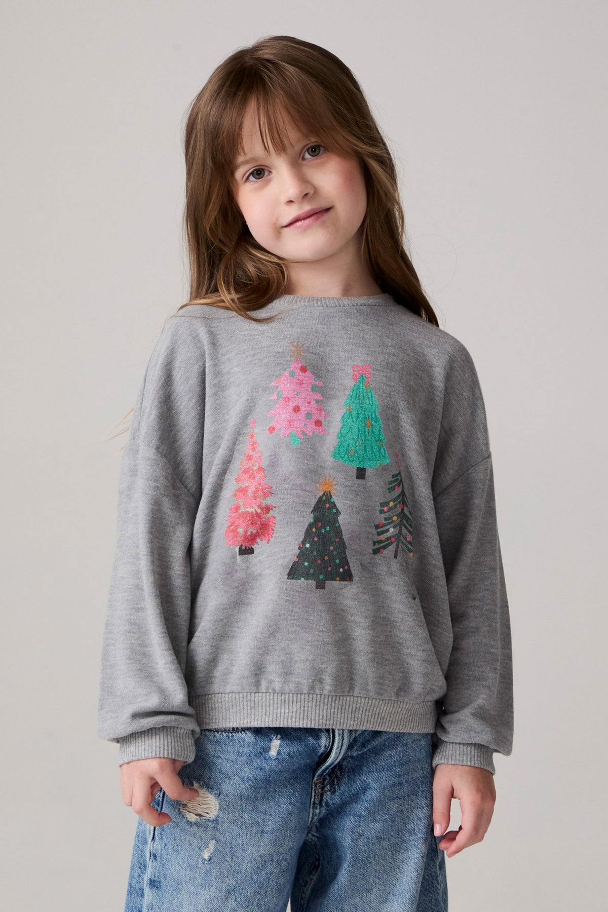 Model wearing Chaser's Festive Trees Girls Pullover in heather grey with distinctive graphic and design details, front view