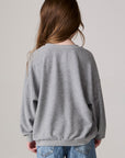 Model wearing Chaser's Festive Trees Girls Pullover in heather grey with distinctive graphic and design details, back view