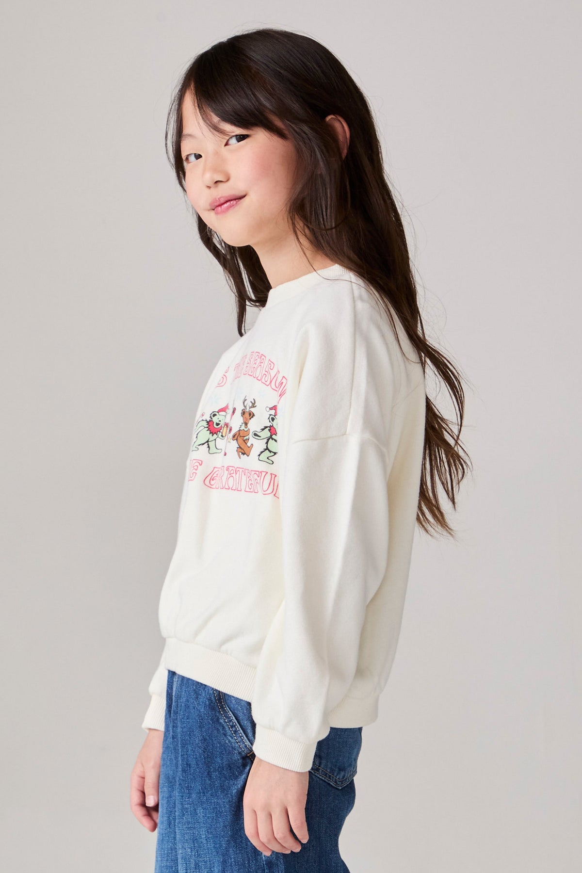 Model wearing Chaser's Grateful Dead 'Tis the Season Girls Pullover in whisper white with Grateful Dead graphic, side view