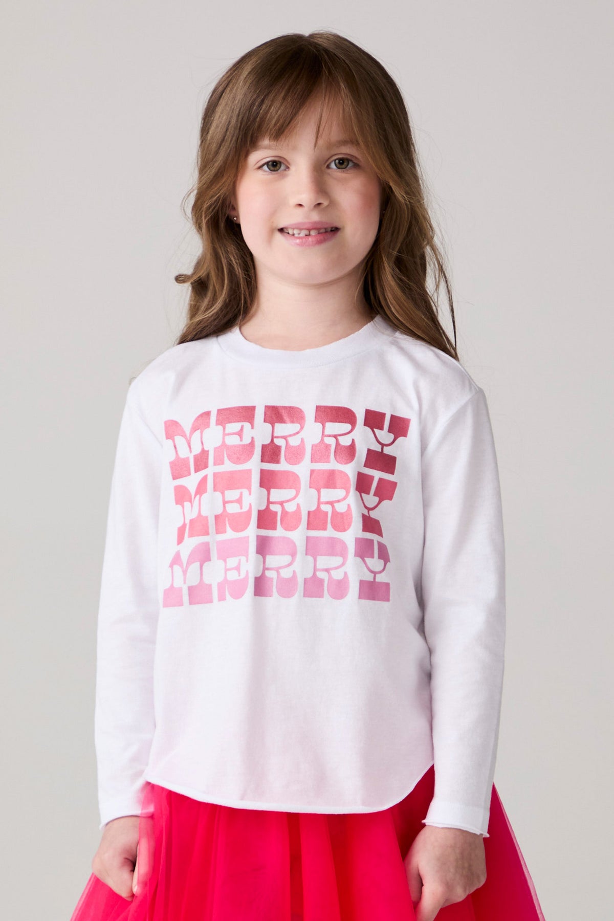 Model wearing Chaser's Merry Girls Long Sleeve Tee in white with pink and red Merry lettering, front view