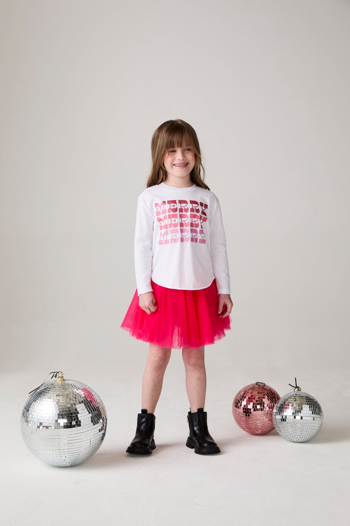 Model wearing Chaser's Merry Girls Long Sleeve Tee in white with holiday lettering, editorial view