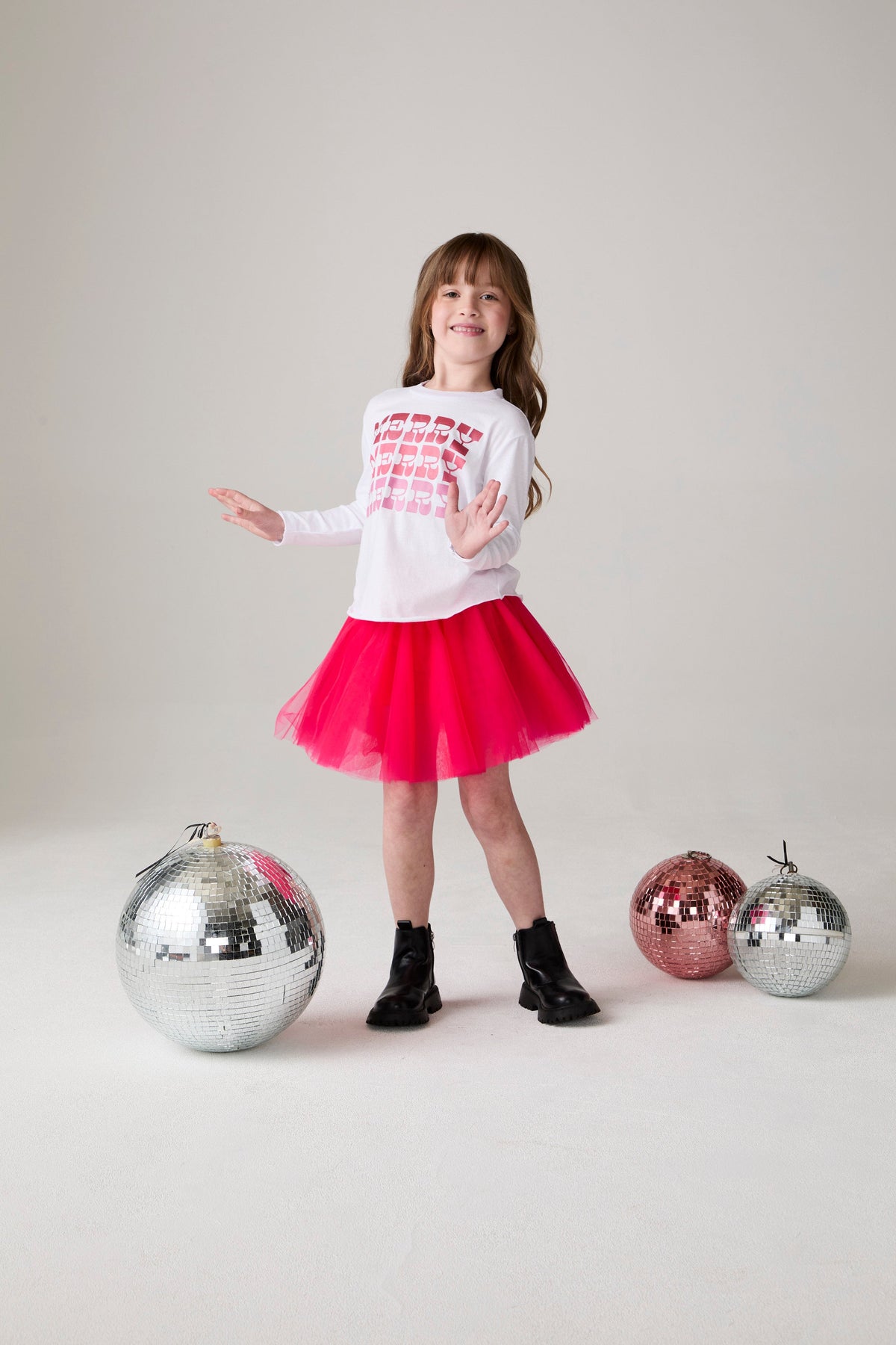 Model wearing Chaser's Merry Girls Long Sleeve Tee in white with holiday lettering, editorial view