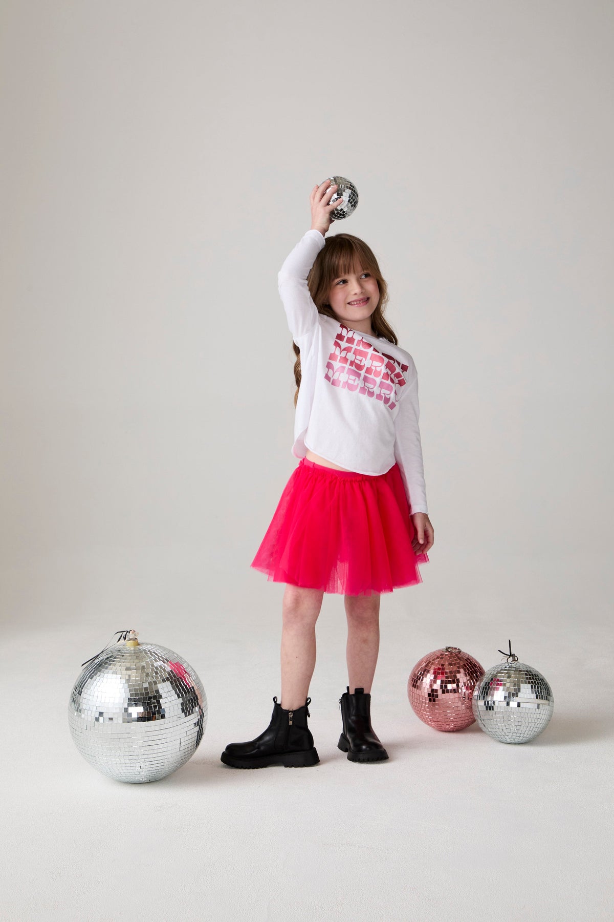 Model wearing Chaser's Merry Girls Long Sleeve Tee in white with holiday lettering, editorial view