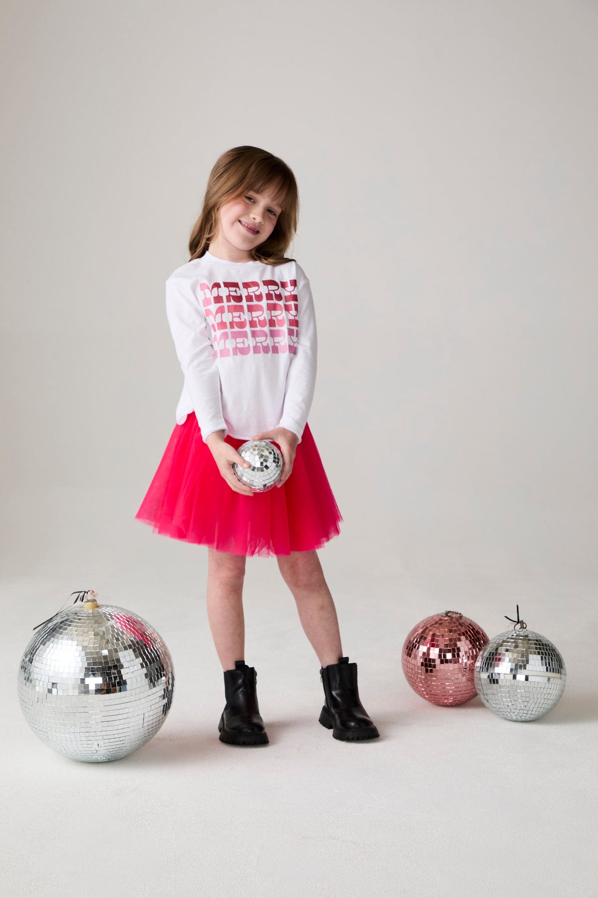 Model wearing Chaser's Merry Girls Long Sleeve Tee in white with holiday lettering, editorial view