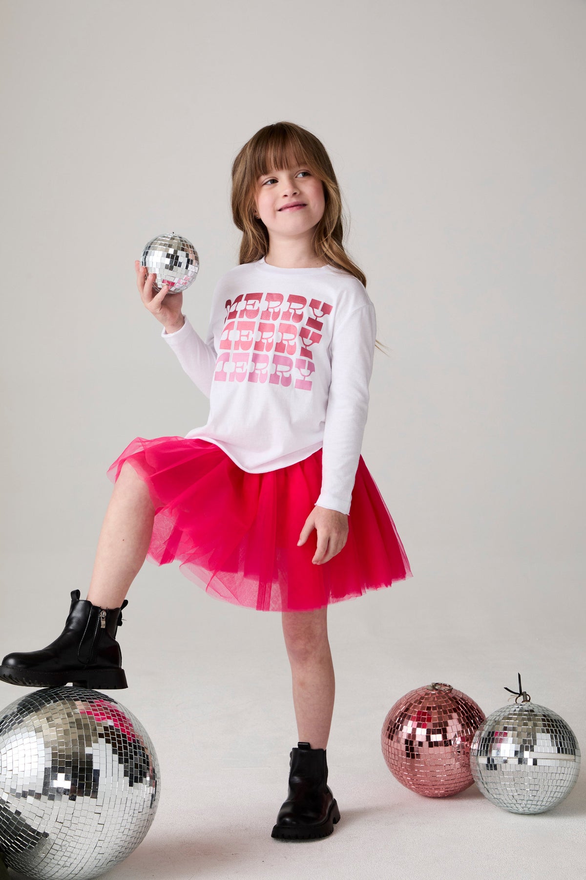 Model wearing Chaser's Merry Girls Long Sleeve Tee in white with holiday lettering, editorial view