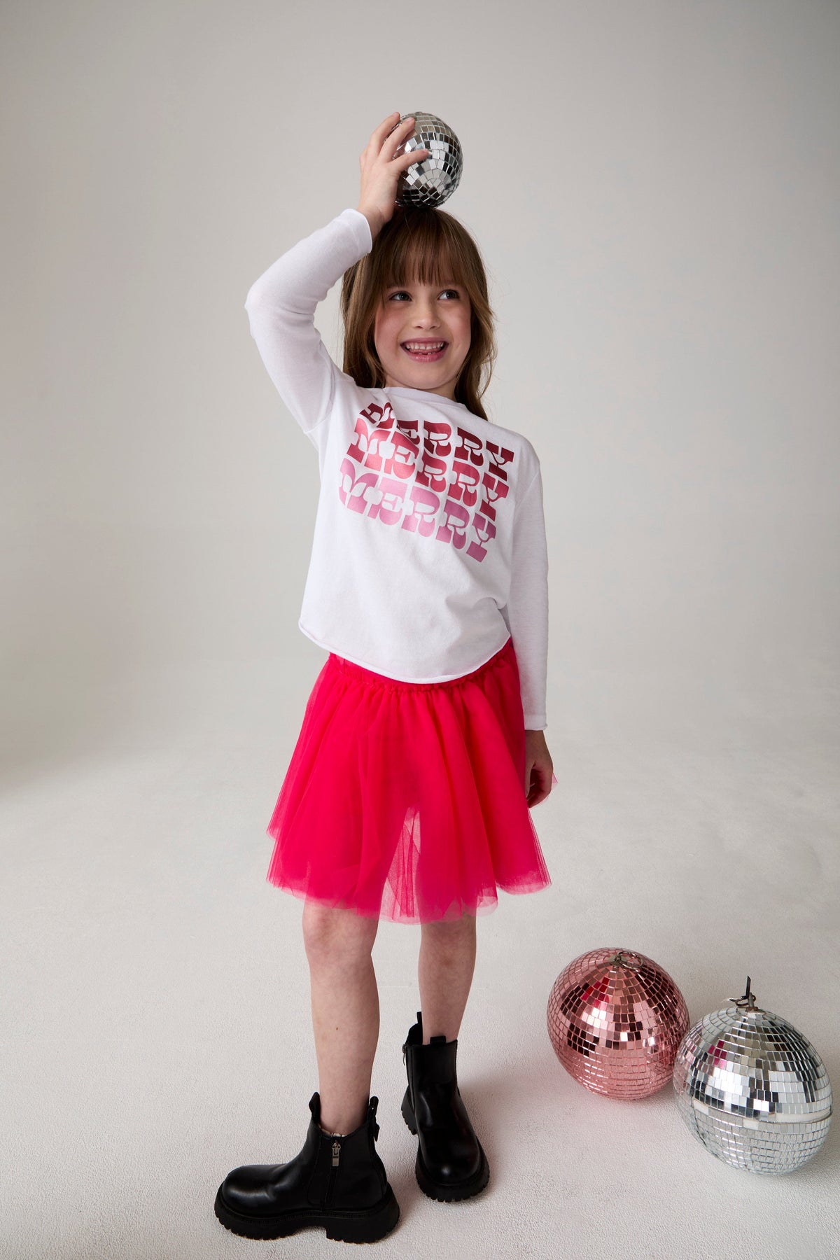 Model wearing Chaser's Merry Girls Long Sleeve Tee in white with holiday lettering, editorial view