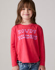 Model wearing Chaser's Howdy Holidays Girls Long Sleeve Tee in hibiscus with western holiday graphic, front view