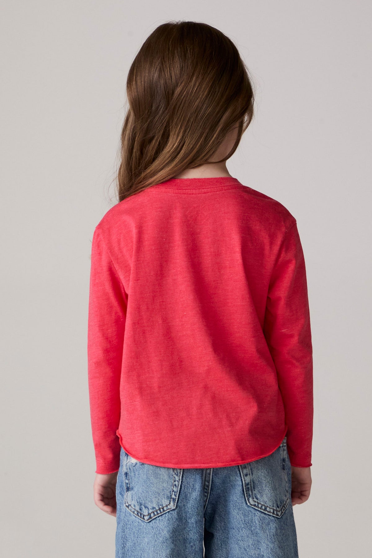 Model wearing Chaser's Howdy Holidays Girls Long Sleeve Tee in hibiscus with western holiday graphic, back view