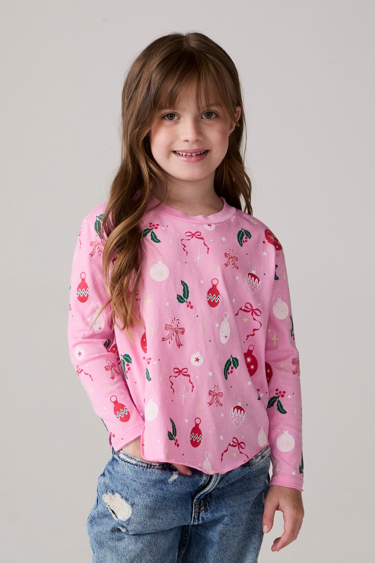 Model wearing Chaser's Yummy Holidays Girls Long Sleeve Tee in camelia pink with holiday treat print, front view
