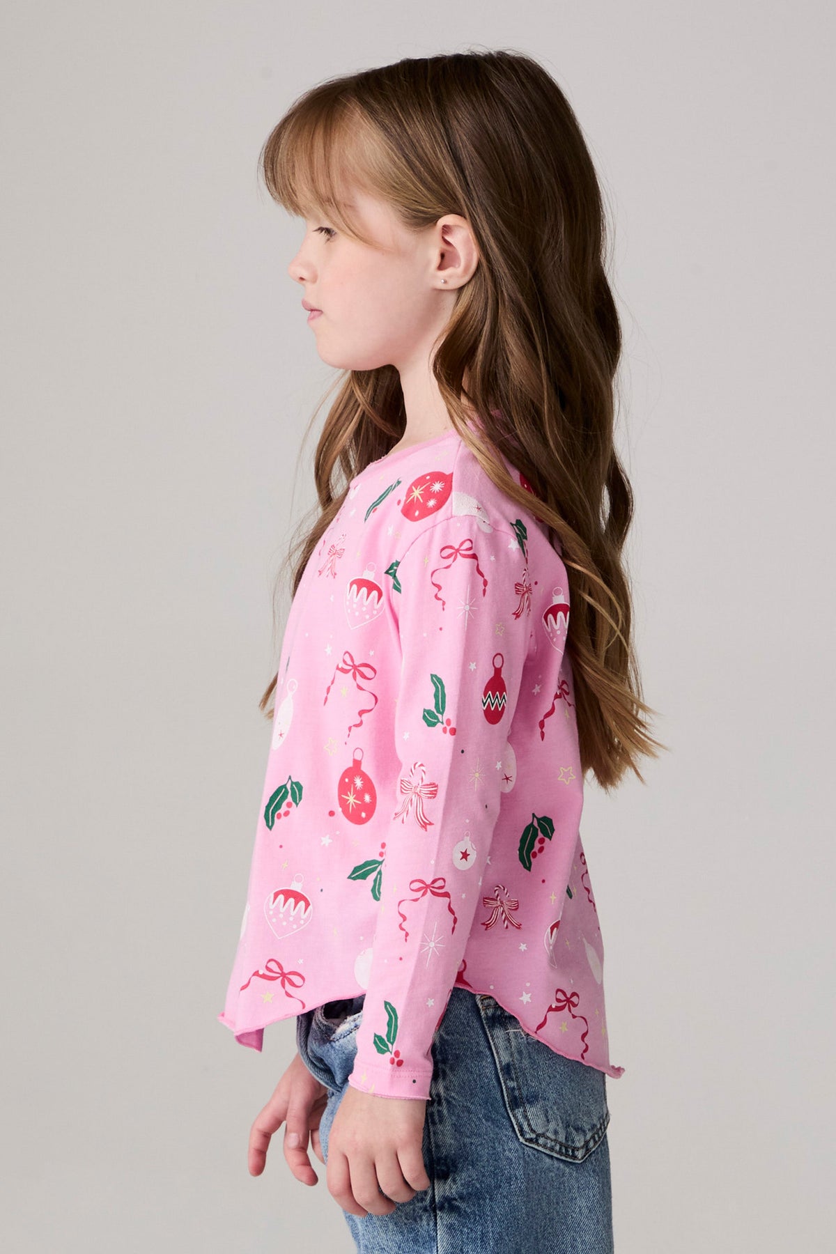 Model wearing Chaser's Yummy Holidays Girls Long Sleeve Tee in camelia pink with holiday treat print, side view