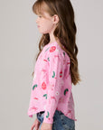 Model wearing Chaser's Yummy Holidays Girls Long Sleeve Tee in camelia pink with holiday treat print, side view