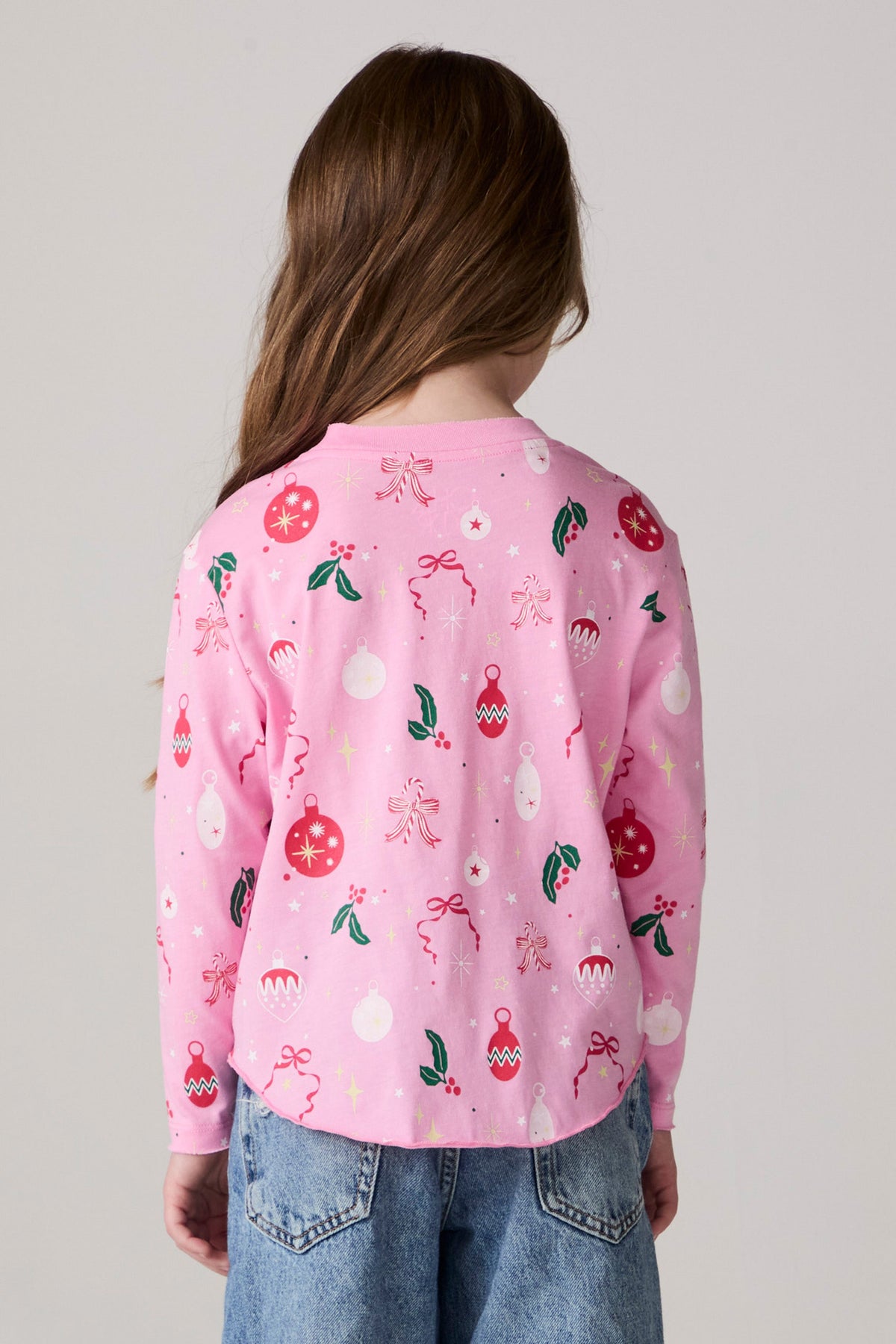 Model wearing Chaser's Yummy Holidays Girls Long Sleeve Tee in camelia pink with holiday treat print, back view