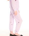 Side view of girl wearing Chaser’s pink Love Pants with heart prints on a white background