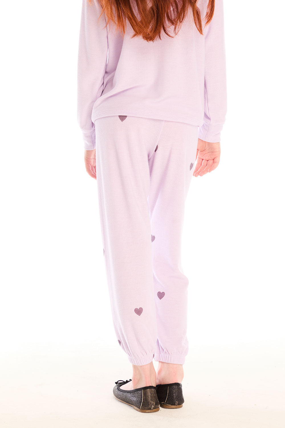 Back view of girl wearing Chaser’s pink Love Pants with heart prints on a white background