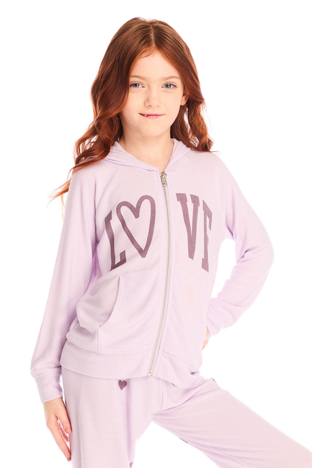 Girl wearing Chaser’s light pink Love Zip Up Hoodie with ‘LOVE’ printed on it against a white background
