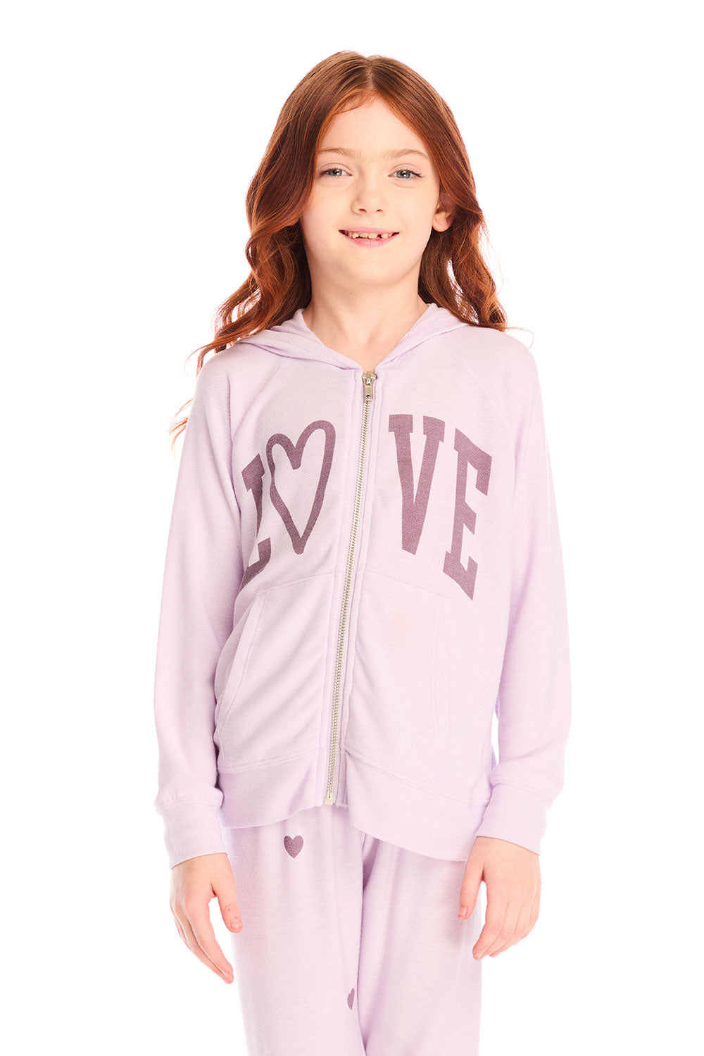 Girl wearing Chaser’s light pink Love Zip Up Hoodie with ‘LOVE’ printed on it against a white background