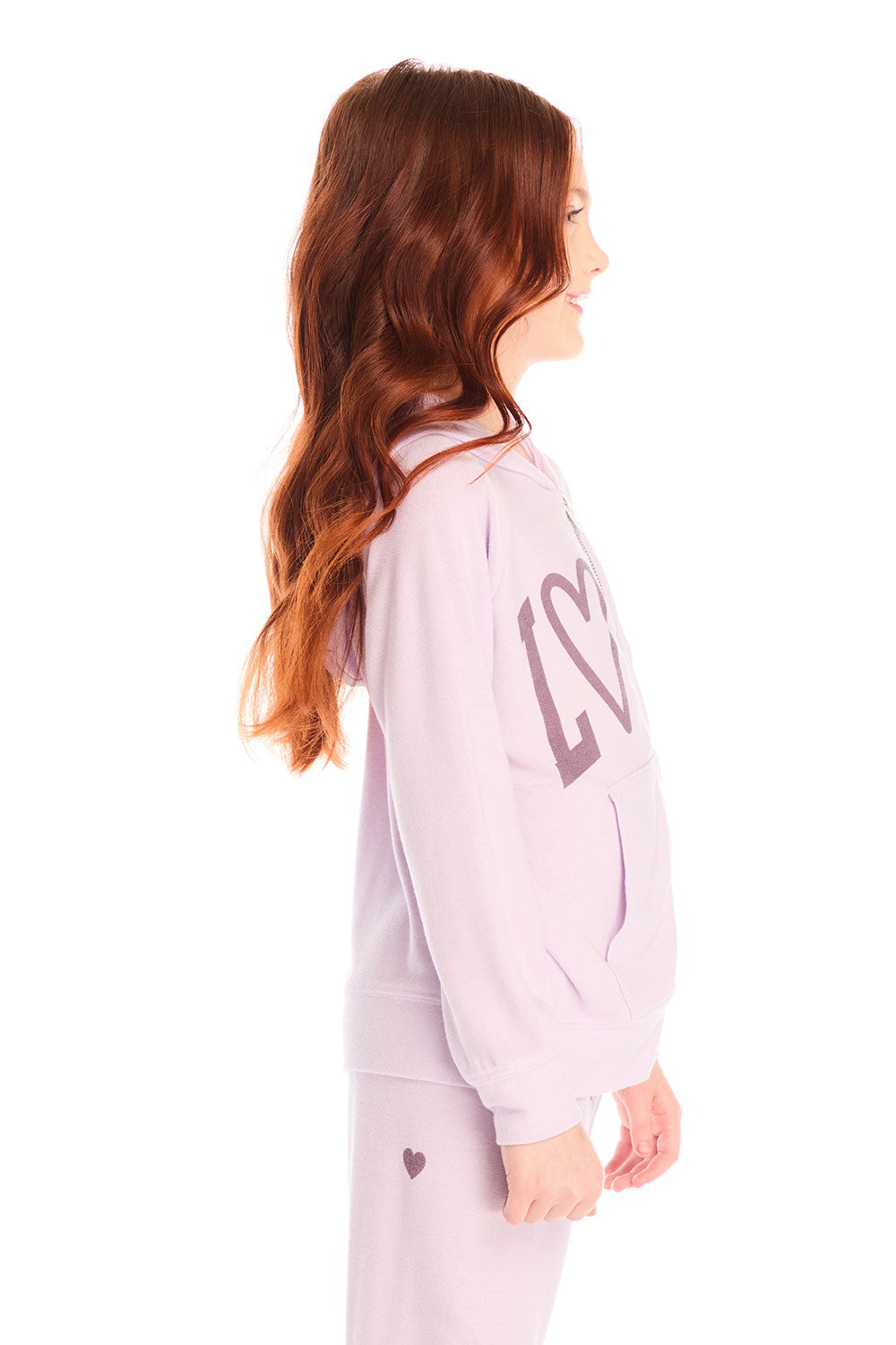 Side view of girl wearing Chaser’s light pink Love Zip Up Hoodie with ‘LOVE’ print against a white background