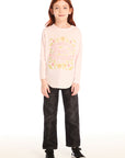 Full body view of girl wearing Chaser’s light pink The Beatles Strawberry Fields Forever Long Sleeve with floral design and black pants on a white background